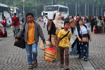Para penumpang di kawasan Monumen Nasional, Jakarta, Indonesia, membawa bagasi masing-masing ketika orang ramai mula pulang ke kampung halaman lebih awal menjelang sambutan Aidilfitri. Langkah itu hasil gabungan dasar ‘bekerja dari mana-mana’ (WFA) untuk penjawat awam serta cuti sekolah yang bermula lebih awal.