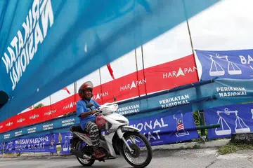 PROSES PILIH KERAJAAN: Seorang penunggang motosikal melintasi bendera dan sepanduk parti semasa kempen pilihan raya umum Malaysia di Ipoh, Perak, awal bulan ini. - Foto REUTERS