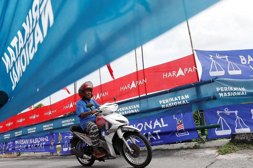 PROSES PILIH KERAJAAN: Seorang penunggang motosikal melintasi bendera dan sepanduk parti semasa kempen pilihan raya umum Malaysia di Ipoh, Perak, awal bulan ini. - Foto REUTERS