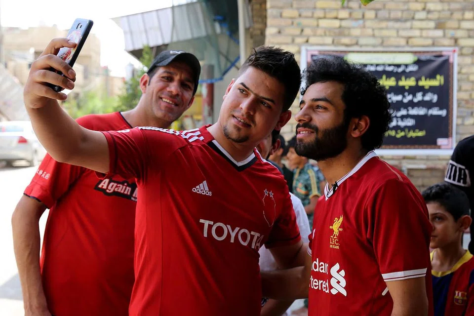 JADI 'BURUAN' PEMINAT: Hussein Ali (kanan) kerap disapa dan diminta bergambar oleh mereka yang sering keliru dan menyangka beliau merupakan bintang bola sepak Liverpool, Mohamed Salah. - Foto AFP