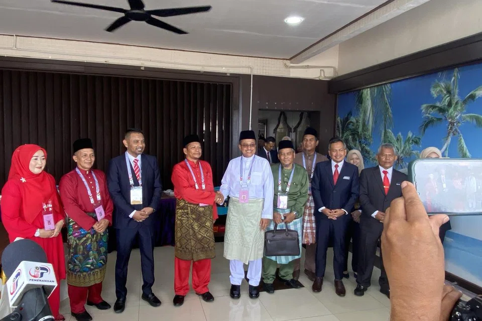 SELESAI PROSES SERAH BORANG: Menteri Besar Terengganu, Datuk Seri Dr Ahmad Samsuri Mokhtar, calon PN-PAS (tengah, berbaju Melayu putih); bersalaman dengan Encik Suhaimi Sulaiman, calon PH-Amanah, selepas penyerahan borang pencalonan di Pusat Penamaan Calon di Pejabat Daerah dan Tanah Marang pada pagi Sabtu.
