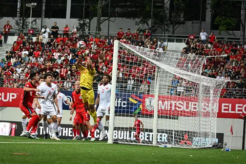 Penjaga gawang Vietnam, Nguyen Dien Trieu, melompat tinggi untuk menyelematkan umpanan dari pemain Singa. 