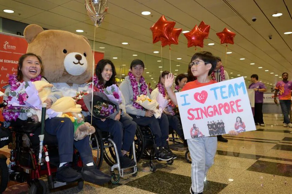 Penyokong Team Singapore, Caleb Tan (kanan), melambai kepada atlet negara selepas bergambar bersama mereka. 