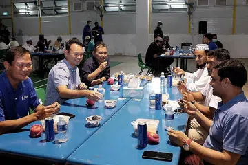 BERBUKA BERSAMA: Encik Zaqy (dua dari kiri), Encik Saat (tiga dari kiri) dan Encik Tung (paling kiri) berbuka bersama pekerja migran dari Tuas View Dormitory. - Foto BH oleh KHALID BABA