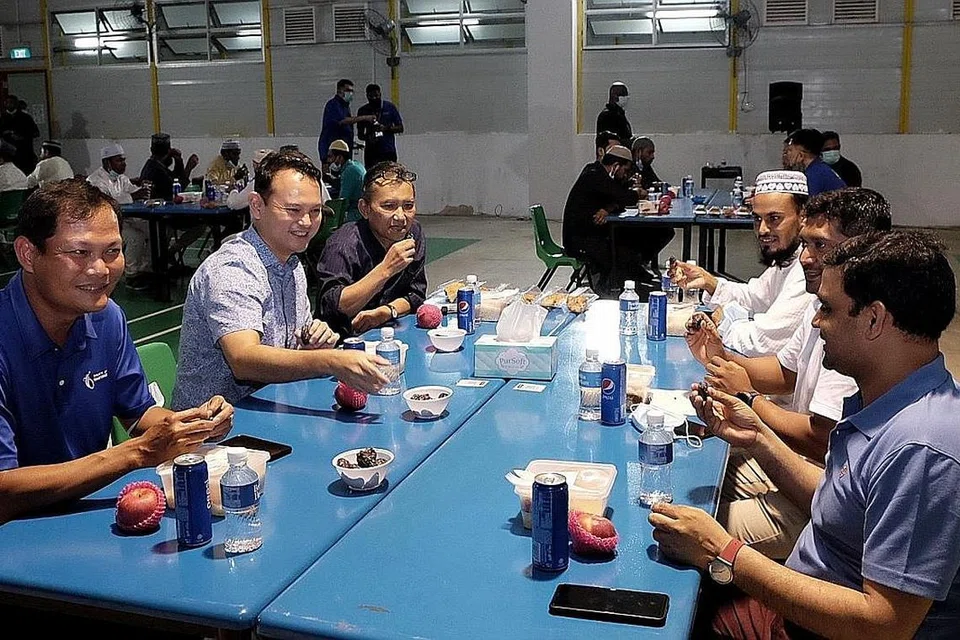 BERBUKA BERSAMA: Encik Zaqy (dua dari kiri), Encik Saat (tiga dari kiri) dan Encik Tung (paling kiri) berbuka bersama pekerja migran dari Tuas View Dormitory. - Foto BH oleh KHALID BABA