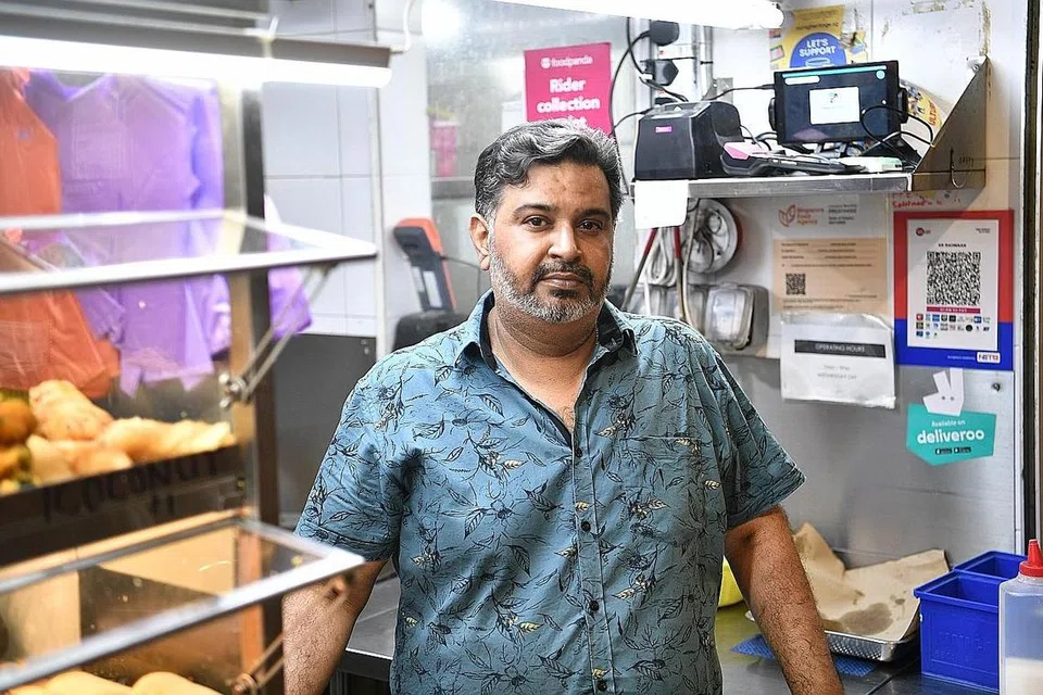 TAWAR KEMUDAHAN: Encik Samsudin Abdul Rahman, 46 tahun, menawarkan khidmat pembayaran elektronik bagi kemudahan pelanggan gerainya di Pusat Penjaja Pasir Ris . - Foto BH oleh ARIFFIN JAMAR