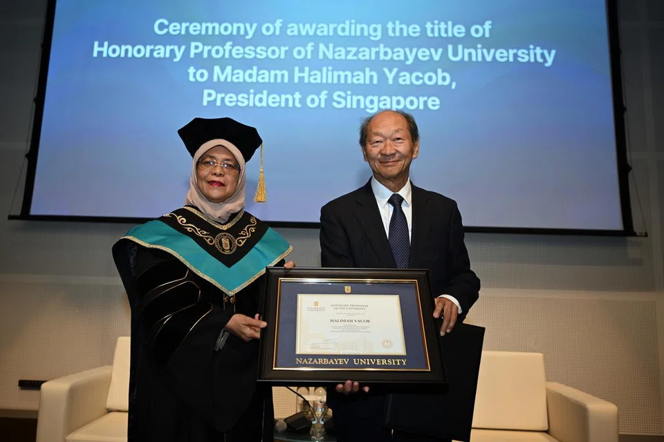 TERIMA ANUGERAH: Presiden Singapura, Presiden Halimah Yacob,  mengenakan gaun sambil menerima jawatan profesor kehormat daripada Presiden Universiti Nazarbayev, Encik Shigeo Katsu, pada Selasa.