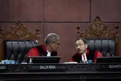 Ketua Hakim Mahkamah Perlembagaan, Dr Suhartoyo (kanan) berbincang dengan Timbalan Ketua Hakim, Profesor Dr Saldi Isra, semasa prosiding semakan kehakiman terhadap Undang-Undang Tentera Indonesia (TNI) di Mahkamah Perlembagaan, Jakarta pada 23 Jun 2025. Dalam sesi itu, Dr Saldi menyoal wakil pemerintah dan Dewan Perwakilan Rakyat (DPR) mengenai sebab pindaan undang-undang tersebut melampaui arahan mahkamah yang hanya berkaitan dengan semakan umur persaraan pegawai tentera.