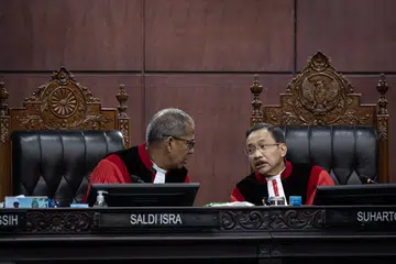 Ketua Hakim Mahkamah Perlembagaan, Dr Suhartoyo (kanan) berbincang dengan Timbalan Ketua Hakim, Profesor Dr Saldi Isra, semasa prosiding semakan kehakiman terhadap Undang-Undang Tentera Indonesia (TNI) di Mahkamah Perlembagaan, Jakarta pada 23 Jun 2025. Dalam sesi itu, Dr Saldi menyoal wakil pemerintah dan Dewan Perwakilan Rakyat (DPR) mengenai sebab pindaan undang-undang tersebut melampaui arahan mahkamah yang hanya berkaitan dengan semakan umur persaraan pegawai tentera.