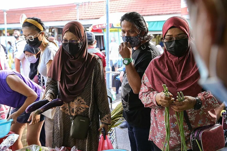 BELI BAHAN DI PASAR: Cik Siti Sarah, Encik Haslan dan Cik Surati membeli bahan-bahan untuk memasak juadah mereka untuk pekerja Malaysia yang masih berada di Singapura Hari Raya ini. - Foto BH oleh YONG LI XUAN