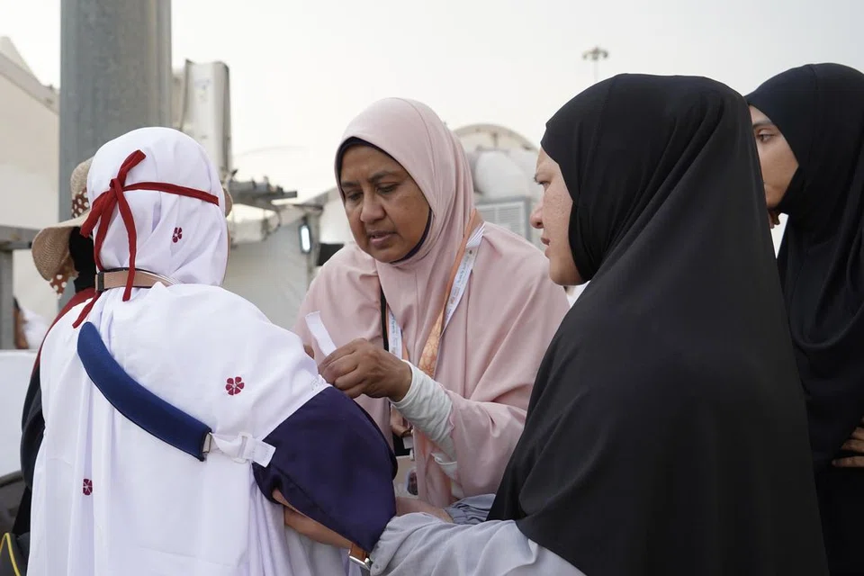 Seorang jururawat SPAO, Cik Sabariah Mohd Said (merah jambu), membantu seorang ahli jemaah.           