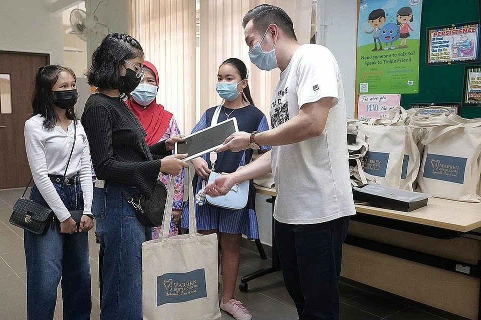 DERMA AMAL: Dr Andy Joshua Warren (kanan), memberi tablet komputer kepada penerima bantuan Persatuan Kanak-Kanak Singapura Nur Darwisyah (berbaju hitam) dan Nur Insyirah (berbaju putih) di cawangan Yishun persatuan itu semalam. Bersama mereka adalah nenek mereka, Cik Siti Rogaiyah (tudung merah). - Foto BH oleh GAVIN FOO