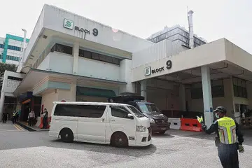 MENUJU KE KREMATORIUM: Dua van putih dilihat keluar daripada rumah mayat SGH. Ini merupakan satu daripada van yang membawa mayat, yang menuju ke Krematorium Mandai. - Foto-foto BH oleh JASON QUAH