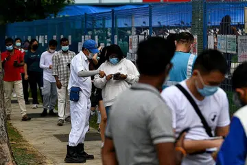 PERLU TUNJUK BUKTI SUDAH DIVAKSIN: Pelajar memandu kelihatan sedang beratur sambil menunjukkan bukti vaksinasi mereka untuk masuk ke Pusat Memandu Bukit Batok. - Foto BH oleh LIM YAOHUI