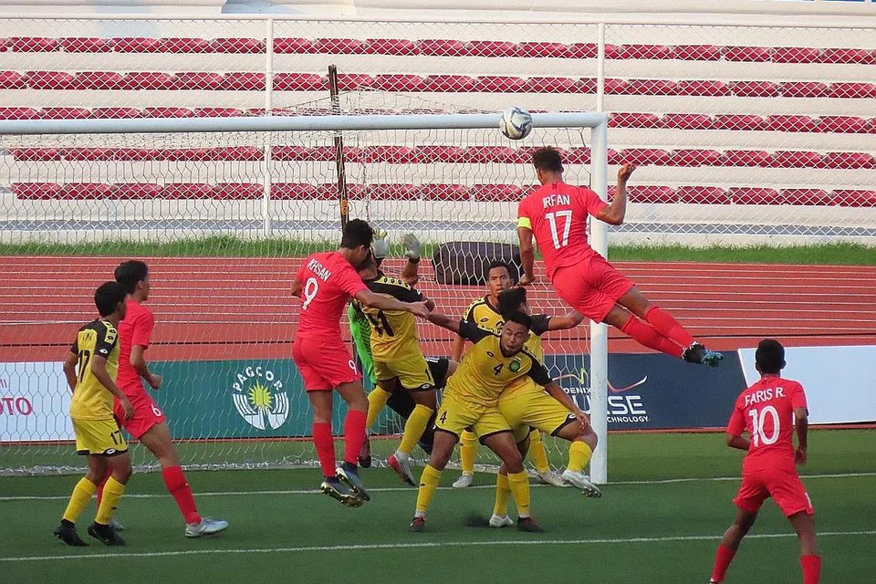 MISI CARI GOL: Irfan (jersi 17) cuba menanduk masuk bola ke dalam gawang lawan dalam kemenangan 7-0 Singapura ke atas Brunei di Stadium Memorial Rizal semalam. - Foto BH oleh ZULAIQAH ABDUL RAHIM