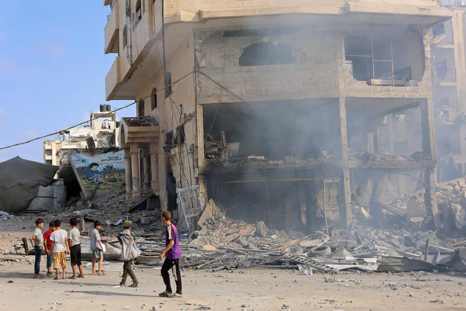 Sekumpulan kanak-kanak Palestin berdiri di hadapan bangunan yang musnah akibat serangan udara Israel di Jalan Al-Jalaa, Bandar Gaza, pada 24 Julai 2026. Kabinet Keselamatan Israel baru-baru ini meluluskan projek perintis di Rafah yang membolehkan Lembaga Keamanan dan Pasukan Penstabilan Antarabangsa (ISF) memasuki Gaza bagi memulihkan perkhidmatan asas serta membuka laluan kepada pentadbiran Jawatankuasa Nasional bagi Pentadbiran Gaza (NCAG), ketika sebahagian besar wilayah itu terus musnah akibat perang yang berlarutan sejak Oktober 2023.