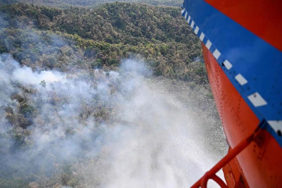 Sebuah helikopter pemadam kebakaran milik Jabatan Pencegahan dan Pengurusan Bencana Thailand (DDPM) menjatuhkan air untuk memadamkan kebakaran hutan di daerah Mae On, wilayah utara Chiang Mai pada 26 Mac 2025. Kebakaran hutan sedang berlaku di beberapa kawasan di utara Thailand, menyumbang kepada peningkatan tahunan pencemaran udara yang turut berpunca daripada aktiviti pembakaran jerami oleh petani bagi menyediakan tanah untuk musim tanaman seterusnya.