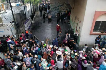 SEKAT MAKANAN: Para penduduk Palestin berasak-asak bagi mendapatkan makanan yang diagihkan oleh sebuah badan amal di Rafah, selatan Gaza pada 17 Disember.