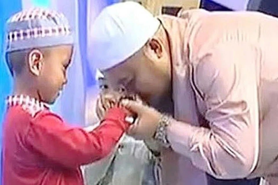 AMBIL BERKAT: Encik Abi Amir (kanan) mengucup tangan hafiz cilik, Musa, kerana terpegun dengan hafalannya. - Foto YOUTUBE