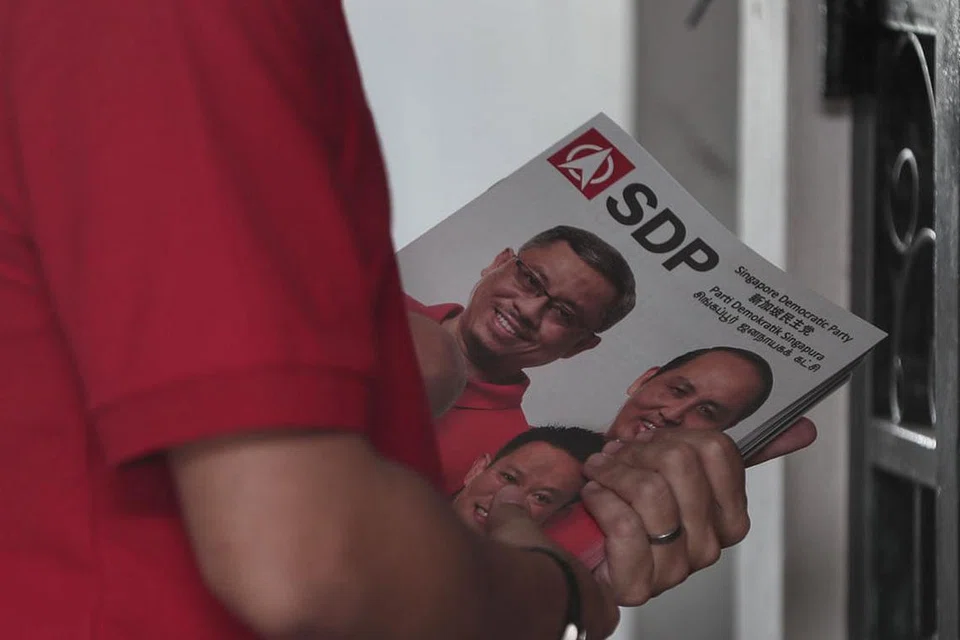 BERKEMPEN: Calon Parti Demokratik Singapura (SDP) (gambar atas) turut turun padang melawat penduduk di rumah mereka. - Foto BH oleh KELVIN CHNG