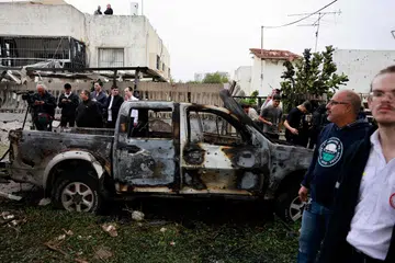 Penduduk dan pegawai keselamatan Israel memeriksa kerosakan kenderaan dan bangunan akibat serangan roket yang dilancarkan dari Lebanon ke kawasan di Petah Tikva dekat ibu kota Tel Aviv pada 24 November.