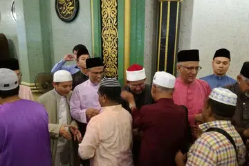 SOLAT BERSAMA: (dari kiri) Encik Masagos, Dr Fatris dan Encik Mohamed bersalam-salaman dengan jemaah di Masjid Sultan selepas menunaikan solat Aidilfitri bersama. 