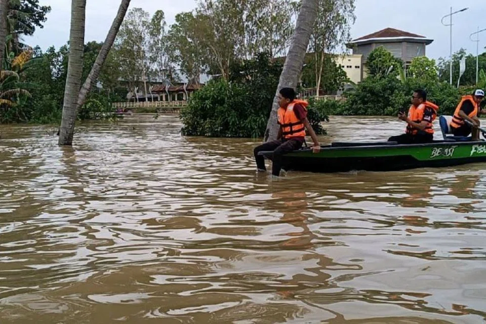 Penduduk, Encik Mohd Helmi Mohd Sobri (kanan), menggunakan bot miliknya untuk membantu memindahkan mangsa banjir dari Kampung Alor Madi, Alor Setar, Kedah.