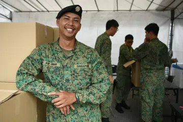 SENYUM SAMBIL BERKHIDMAT: Pegawai Waran Ketiga (3WO) Alif Omar, 40 tahun, dari Batalion ke-30, Jurutera Kombat Singapura bertanggungjawab memastikan sajian dan keperluan peserta segmen Perbarisan Pertahanan Mutlak (TDP) dijaga dengan baik.