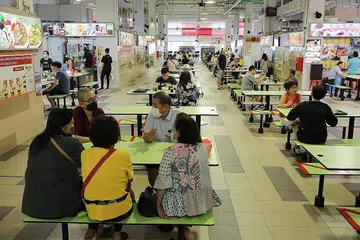 ATURAN DILONGGAR: Sekumpulan lima orang makan semeja di Pusat Penjaja Ci Yuan di Hougang selepas peraturan dilonggarkan. - Foto BH oleh ONG WEE JIN