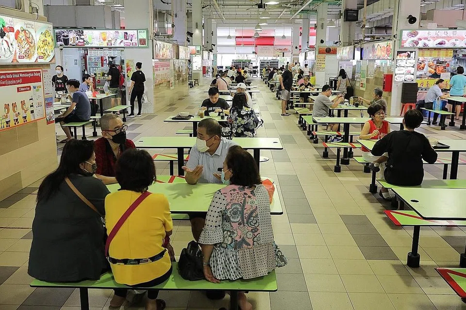 ATURAN DILONGGAR: Sekumpulan lima orang makan semeja di Pusat Penjaja Ci Yuan di Hougang selepas peraturan dilonggarkan. - Foto BH oleh ONG WEE JIN
