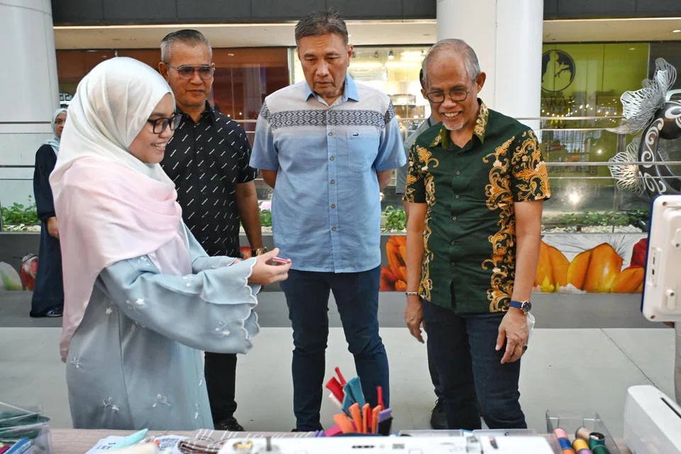 Pemilik ‘Sew Stitchez’, Cik Nur Atiqah Mohamed Rihat, menunjukkan hasil sulaman beliau kepada Menteri Bertanggungjawab bagi Ehwal Masyarakat Islam, Encik Masagos Zulkifli Masagos Mohamad (paling kanan) di ‘SELOKAL 2024’ di Our Tampines Hub. Turut hadir ialah Presiden DPPMS, Encik Abu Bakar Mohd Nor (dua dari kanan) dan Ahli Jawatankuasa DPPMS, Encik Azhar Md Salleh. 