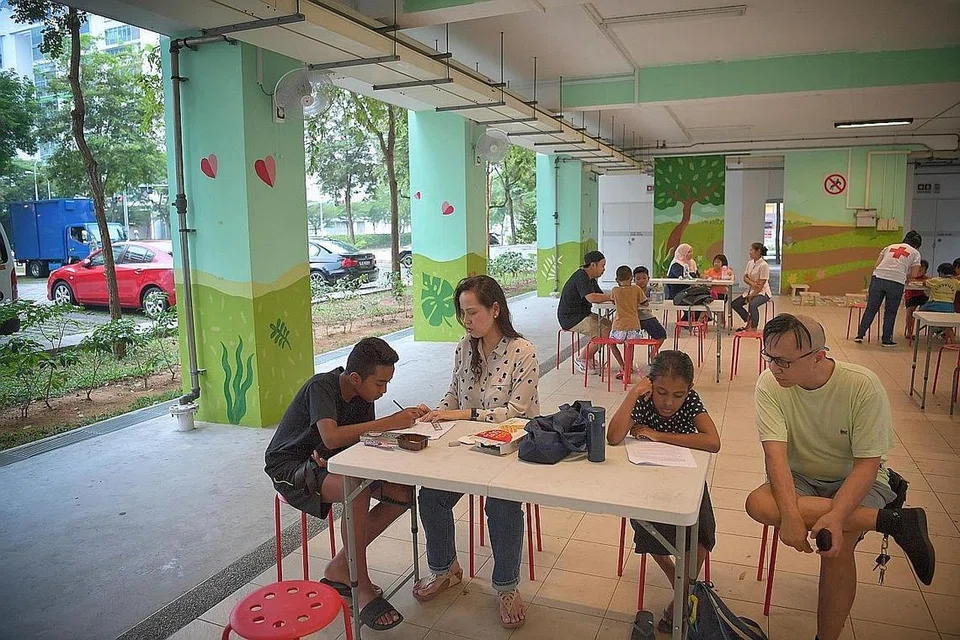TIDAK LAGI SENDIRIAN: Irfan (kiri) dibimbing melakukan tugas sekolah oleh relawan Cik Siti Hawa di bawah program 'Young Hearts@Nee Soon East' kelolaan Palang Merah Singapura (SRC). - Foto BH oleh ARIFFIN JAMAR