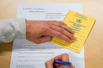 PENJAGAAN KESIHATAN: Satu ilustrasi gambar yang dirakam pada 12 Februari lalu menunjukkan seorang lelaki menandatangi borang persetujuan semasa memegang 'Kad Kuning' atau Sijil Vaksinasi atau Profilaksis Antarabangsa (ICVP). Ia juga dikenali dengan nama 'Carte Jaune' yang dikeluarkan oleh WHO semasa taklimat wajib sebelum vaksinasi Covid-19 di hospital universiti di Halle/Saale, timur Jerman. - Foto AFP