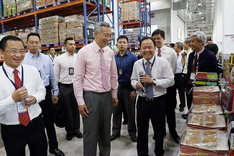 HAB FAIRPRICE: Encik Lee sambil diiringi (paling kiri) Encik Seah Kian Peng, Ketua Pegawai Eksekutif NTUC Fairprice Co-operative, meninjau gudang runcit yang terletak di dalam Hab FairPrice. - Foto THE STRAITS TIMES