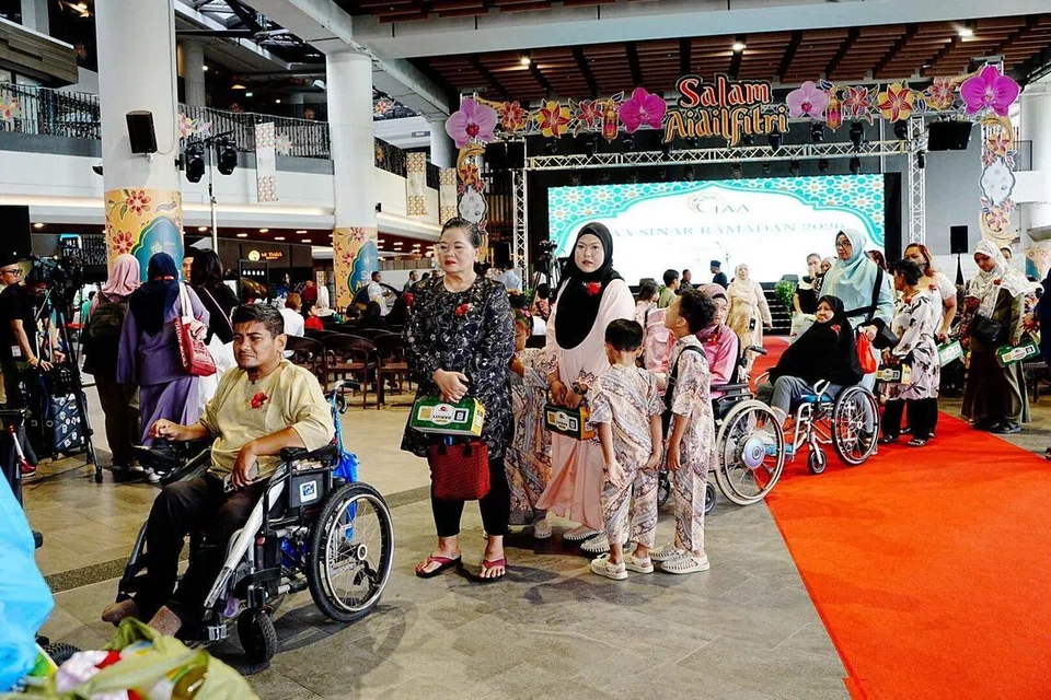 Seramai 55 penerima bantuan TAA bersama anggota keluarga masing-masing beratur untuk menerima bantuan kewangan $500 bagi setiap isi rumah serta troli barangan dapur yang merangkumi bahan masakan dan juadah Hari Raya semasa Majlis Pengagihan Sinar Ramadan yang diadakan di Wisma Geylang Serai pada 15 Mac.