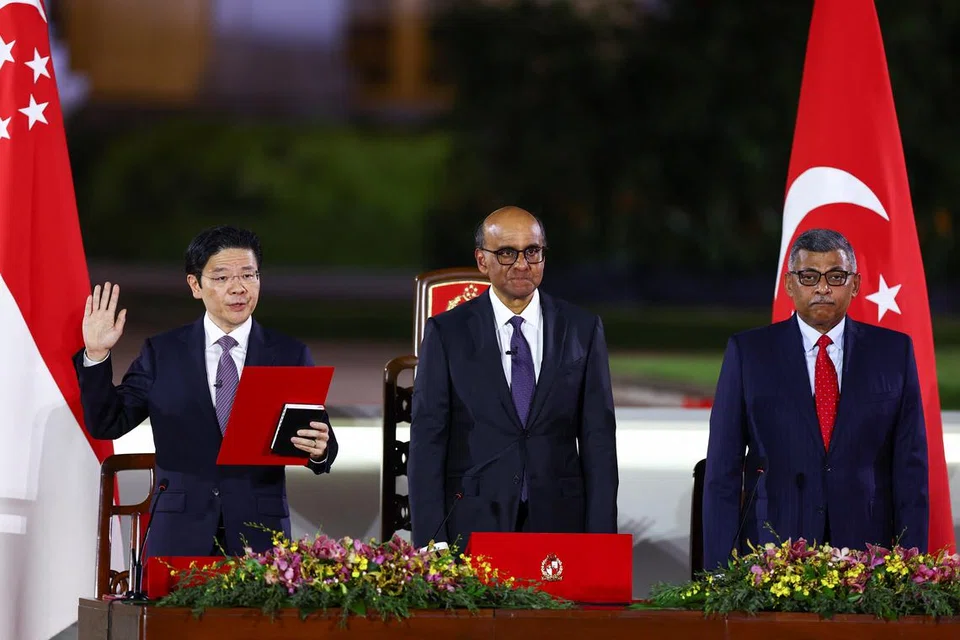 Perdana Menteri, Encik Lawrence Wong (kiri) mengangkat sumpah, sambil disaksikan oleh Presiden Tharman Shanmugaratnam (tengah) dan Hakim Besar, Encik Sundaresh Menon (kanan) pada 15 Mei di Istana.