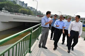 TANGANI BANJIR: Encik Masagos (tengah) telah meninjau kerja-kerja peningkatan yang dijalankan di Longkang Besar Lencongan Pertama Bukit Timah semalam. Menemaninya ialah (kanan sekali) Encik Christopher de Souza (GRC Holland-Bukit Timah) dan pegawai-pegawai PUB yang lain. Longkang itu berupaya menampung 30 peratus lebih banyak air hujan dalam membantu mencegah banjir di kawasan tadahan atas Bukit Timah. - Foto BH oleh NG SOR LUAN