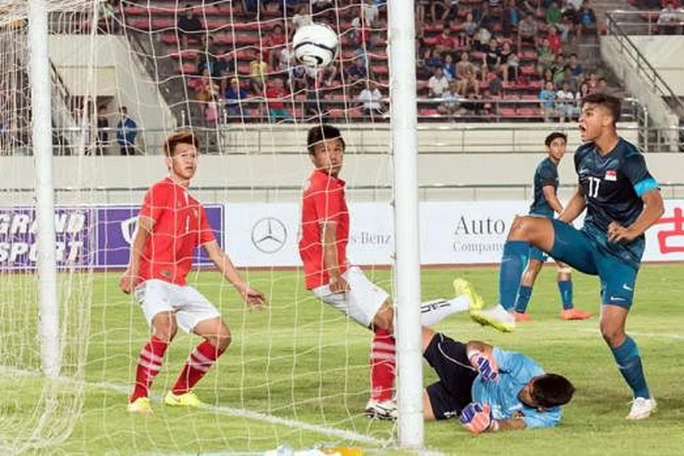 GOL SESIA: Irfan, (jersi biru, paling kanan) menyumbat gol dalam babak pertama, tetapi ia tidak diambil kira kerana pengadil mendakwa beliau telah mengasari penjaga gawang Laos. - Foto PERSATUAN BOLA SEPAK SINGAPURA