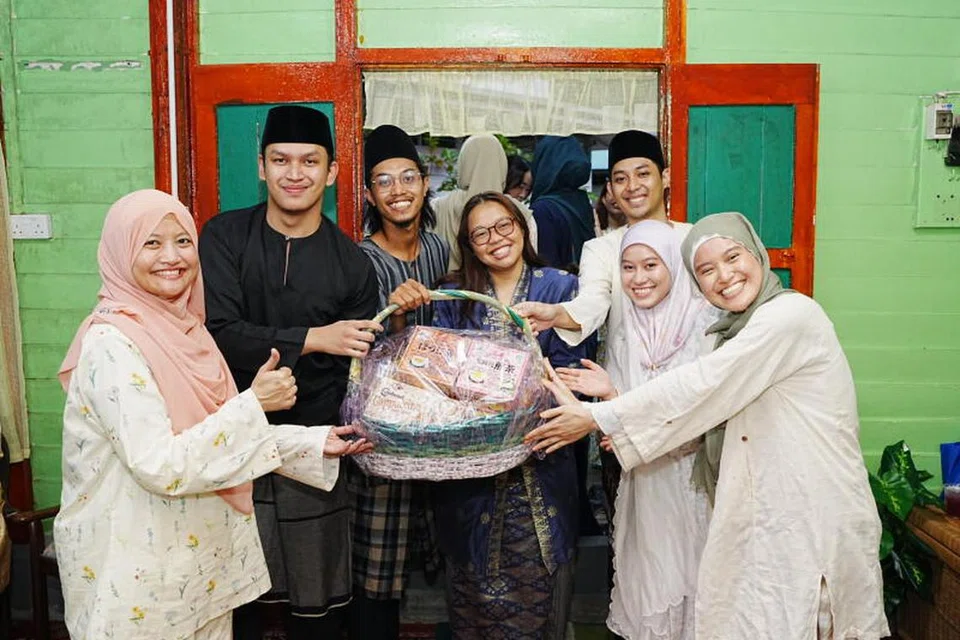 Editor Audiens dan Perkembangan Berita Harian, Cik Norhaiza Hashim (kiri), menyampaikan hadiah kepada pemenang permainan berkumpulan di majlis perjumpaan Hari Raya wadah digital BH, OMGxBH, di Kampong Lorong Buangkok. 