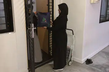 Cik Norsiha Aboo Bakar (kanan), menyerahkan daging korban, yang penyembelihannya dilakukan di Australia, ke rumah penerima bantuan zakat di Yishun. 
