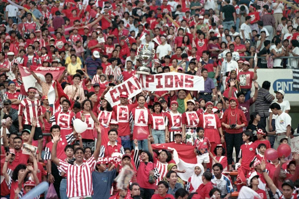 Penyokong setempat bersorakan dan mengangkat kain rentang untuk memberi sokongan kepada pasukan bola sepak kesayangan di Stadium Negara lama di Kallang pada 1994.