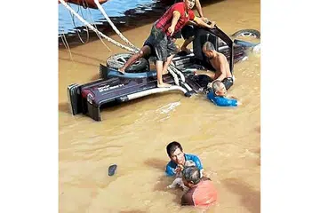 HULUR BANTUAN: Beberapa orang awam melompat ke sungai dalam usaha menarik mangsa keluar dari kenderaan. - Foto THE STAR