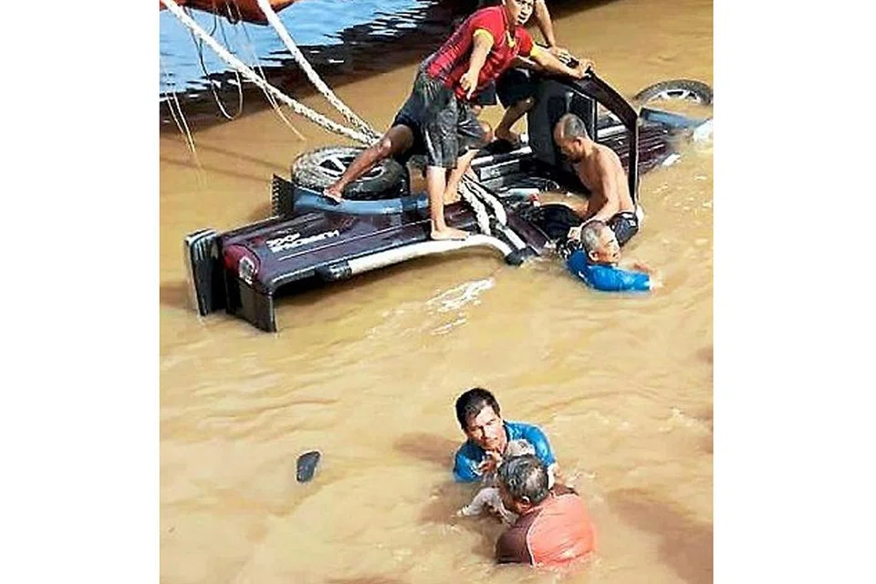 HULUR BANTUAN: Beberapa orang awam melompat ke sungai dalam usaha menarik mangsa keluar dari kenderaan. - Foto THE STAR