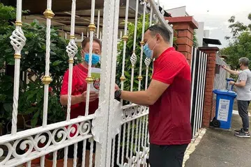 TINGKAT KESEDARAN AWAM: Aktivis akar umbi Encik Mohd Fahmi Aliman (kanan) menyumbang tenaga mengagihkan penghalau nyamuk dan risalah bagi meningkatkan kesedaran awam tentang pencegahan denggi. - Foto FACEBOOK FAHMI ALIMAN