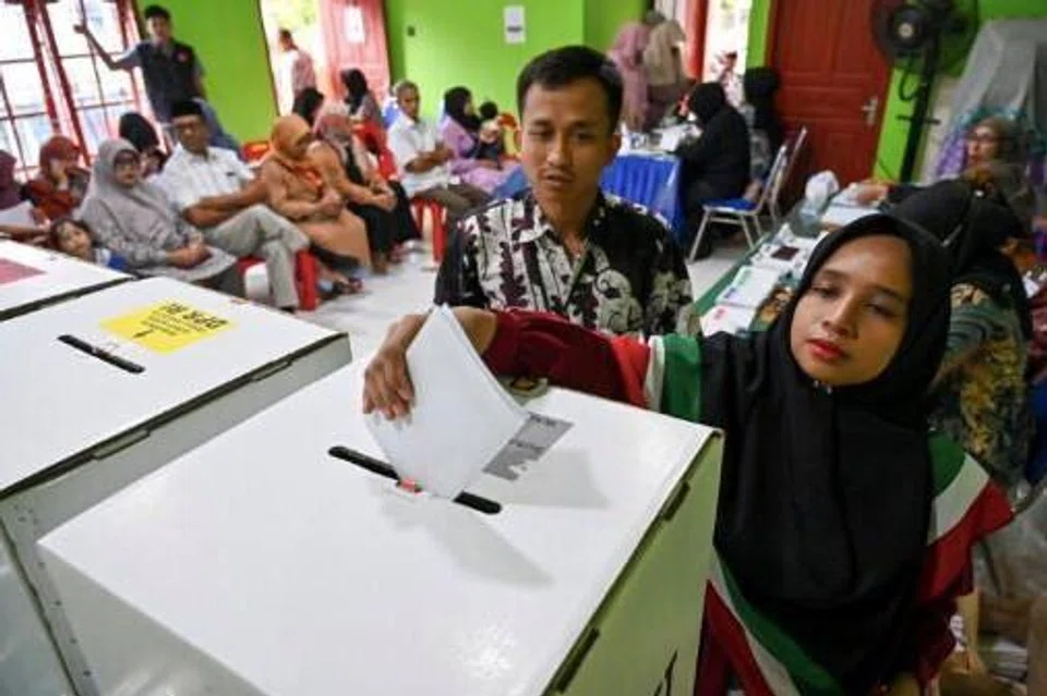 Seorang wanita membuang undi dalam pilihan raya umum 2024 pada 14 Februari di sebuah pusat mengundi di Banda Aceh, Aceh.