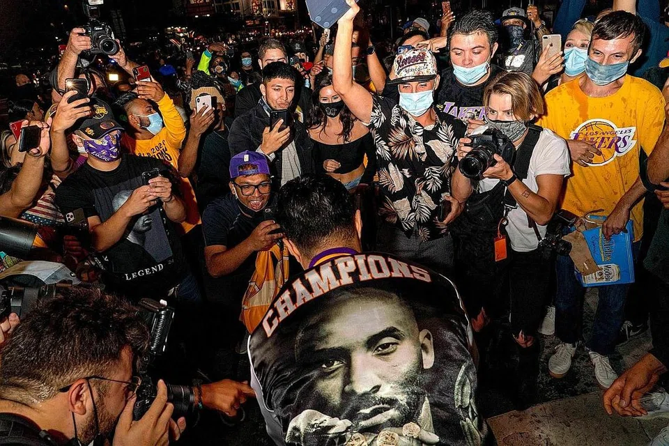 KITA JUARA!: Penyokong LA Lakers menyambut meriah kejayaan yang dinanti-nantikan selepas sedekad menanti dengan bantuan kecemerlangan LeBron James. - Foto AFP