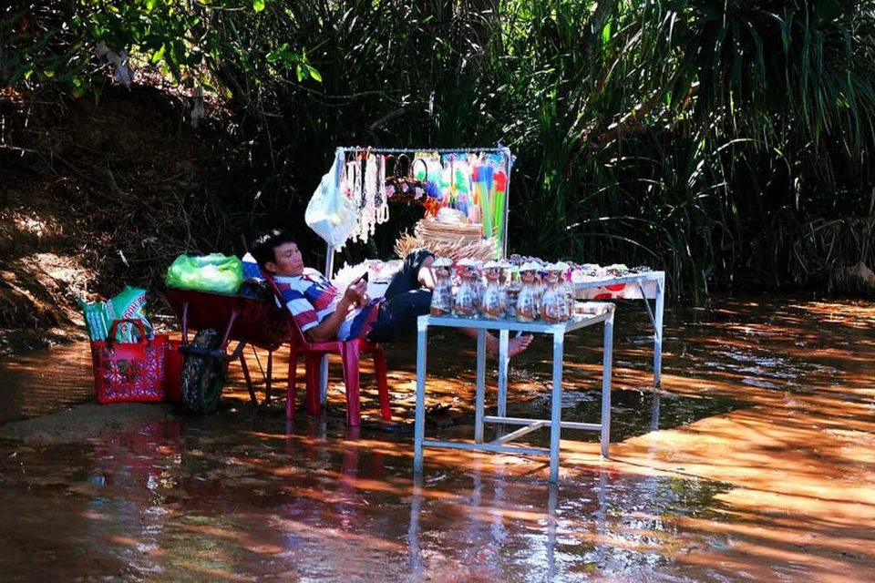MENANTI PELANGGAN: Seorang penjual cendera hati menanti penuh sabar kedatangan pelancong sambil menatap telefon bimbit bagi membeli hasil jualannya untuk dibawa pulang sebagai hadiah buat keluarga dan sahabat handai.