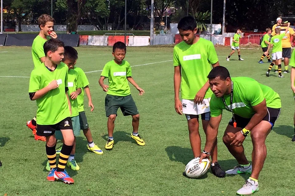 BEGINI CARANYA: Legenda ragbi Fiji, Waisale Serevi (kanan), memberi tunjuk ajar kepada pemain-pemain cilik di satu klinik ragbi yang berlangsung di Padang semalam. - Foto SINGAPORE RUGBY