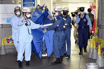 SEGERA MEMBANTU: Pekerja penyelamat dipercayai mengangkat penumpang yang cedera di Stesen Soshigaya-Okura di Tokyo pada Jumaat (6 Ogos). - Foto REUTERS 