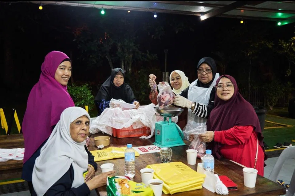 Relawan membungkus daging kambing korban yang telah disembelih di Singapura pada 2023.